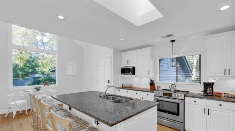 Modern kitchen with a granite island and white cabinets inside a Hilton Head Island vacation rental.